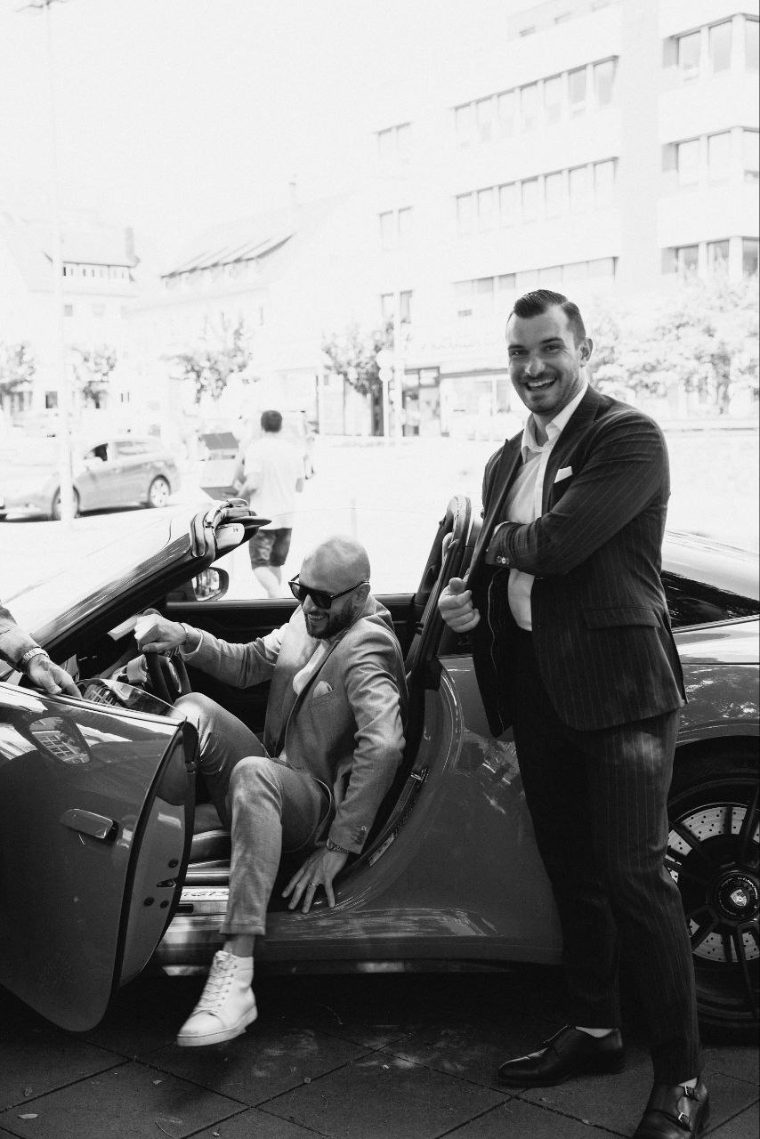 Hochzeitsgesellschaft in Schwarzweiß an einem Auto