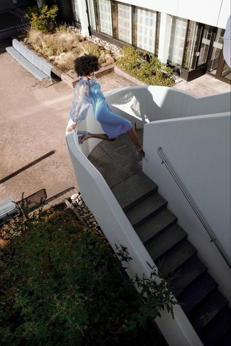 Mode-Aufnahme im hellblauen Kleid auf einer Wendeltreppe